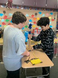 Two boys working on a prosthetic leg on top of a desk