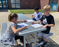 Three students at outside table planning their experiment