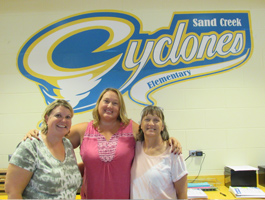 Three staff members standing in front of Cyclones sign